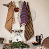 "Elegant kitchen towels in warm browns with striped and checked patterns, displayed against a neutral backdrop."