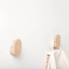 Light wood coat hooks with a smooth, natural finish on a white wall. Simple, modern design.