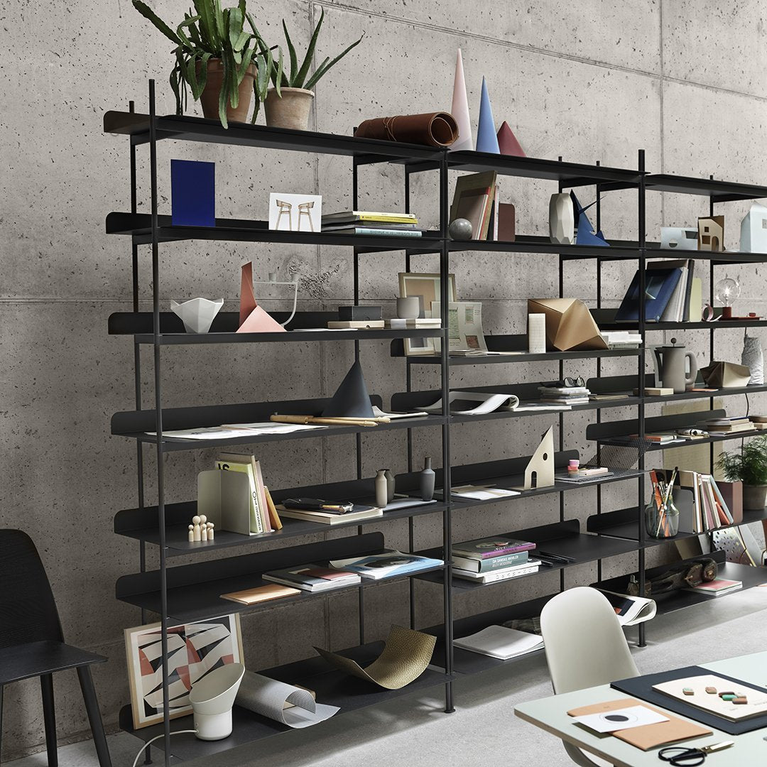 Modern black shelving unit displaying a variety of colorful notebooks and geometric paper patterns.