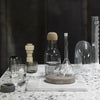"Clear glassware with cork accents on a speckled stone countertop in a modern setting."