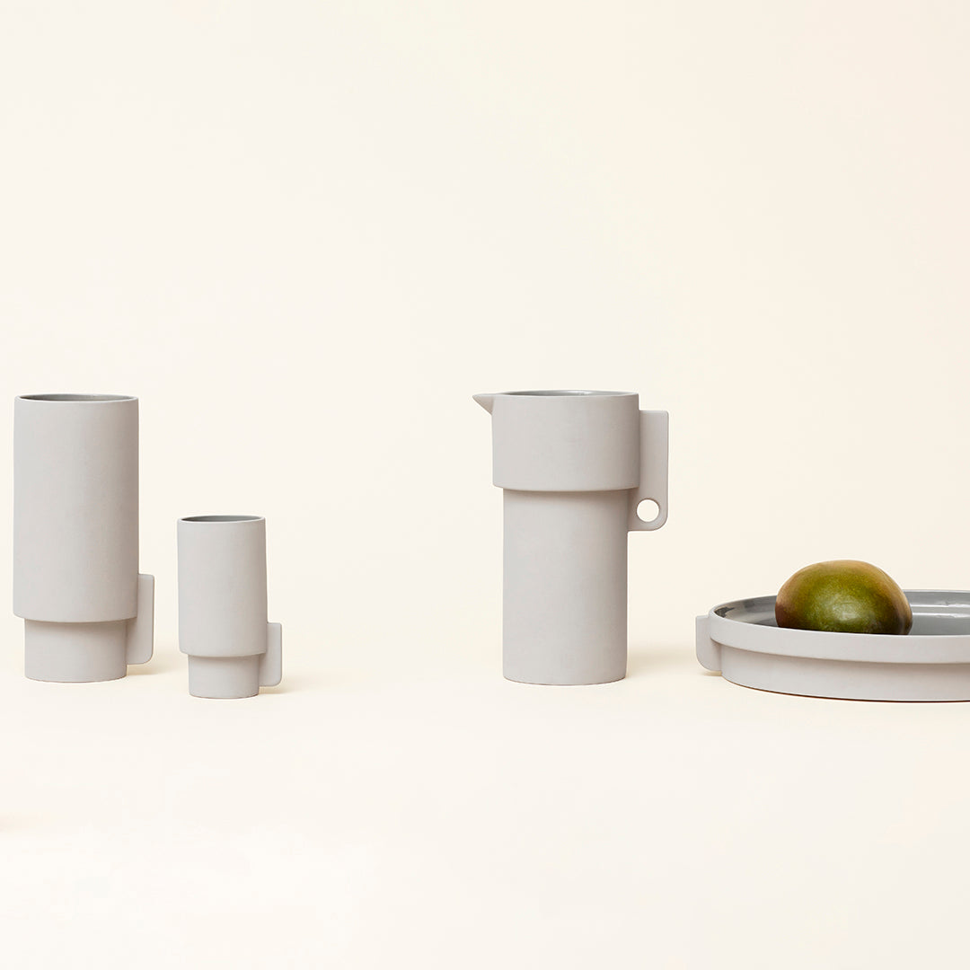 Gray ceramic pitcher and containers with minimalist design, set on a light background with a green lime accent.