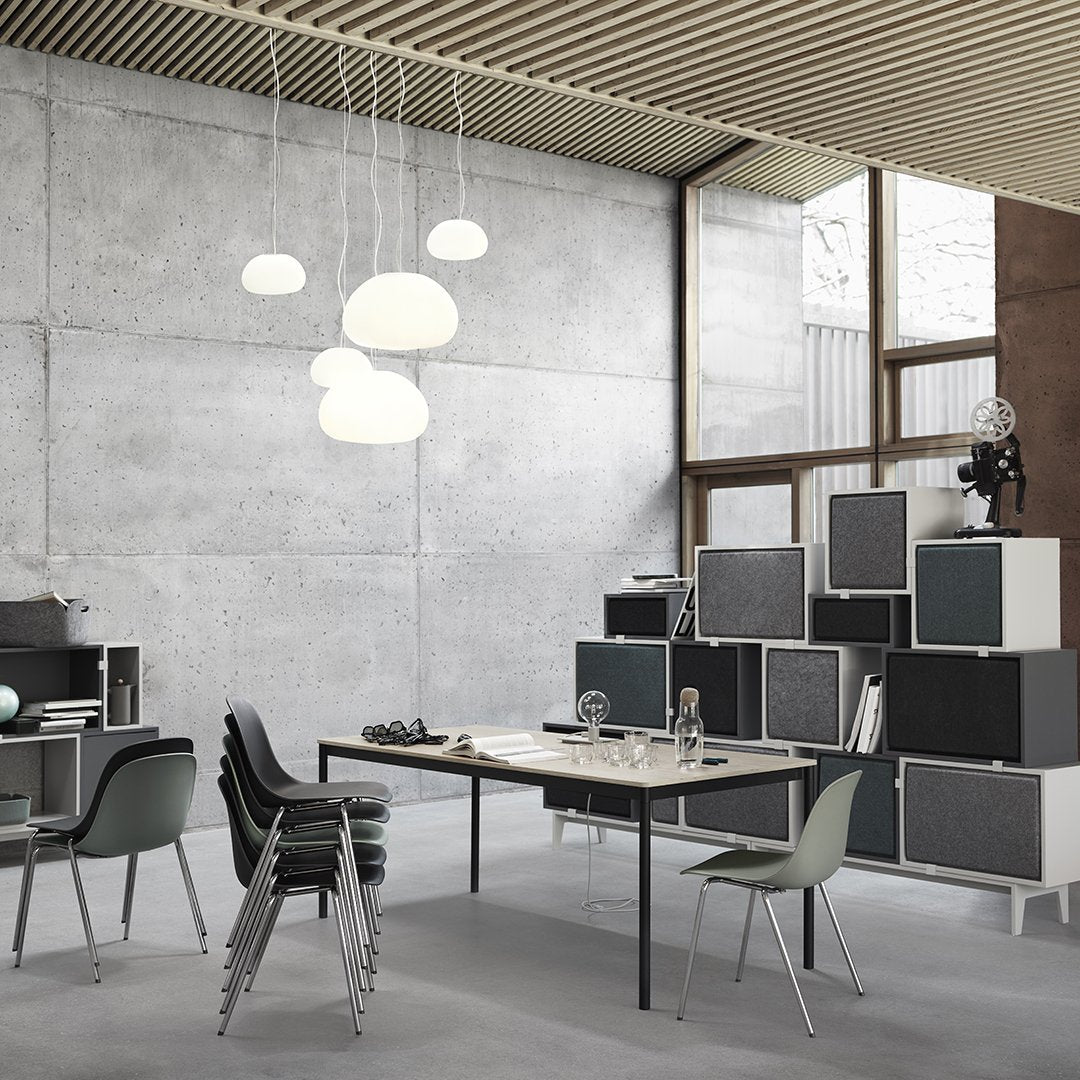 Modern office space featuring gray concrete walls, black and white furniture, and soft white pendant lighting.