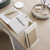 Elegant beige and white notebooks on a light wood table with minimalistic gray and beige accessories.