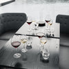 "Elegant glassware set featuring rich reds and yellows atop a dark wood table, with a sleek, modern grey backdrop."