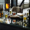 Assorted glasses with golden beers, dark shots, and pops of red, arranged on a rustic table with a reflective surface.