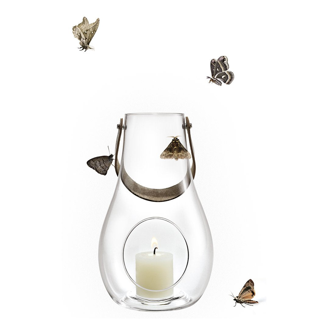 Clear glass lantern with a silver handle, featuring a white candle inside and a whimsical butterfly pattern.