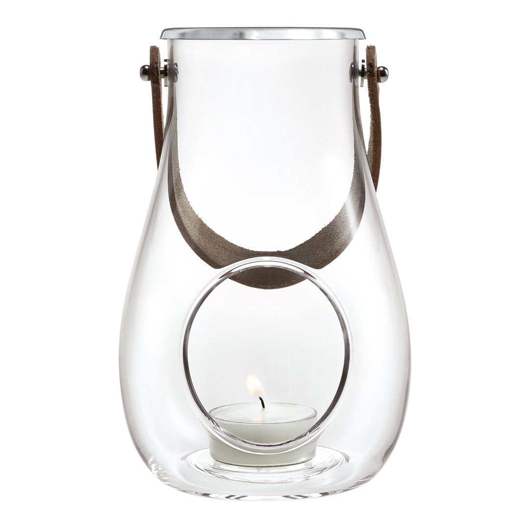 Clear glass lantern with a circular cutout, accented by a brown leather handle and a subtle candle glow.