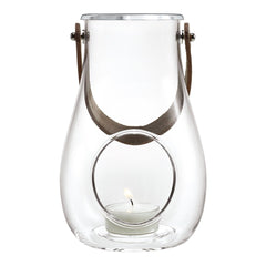 Clear glass lantern with a circular cutout, accented by a brown leather handle and a subtle candle glow.
