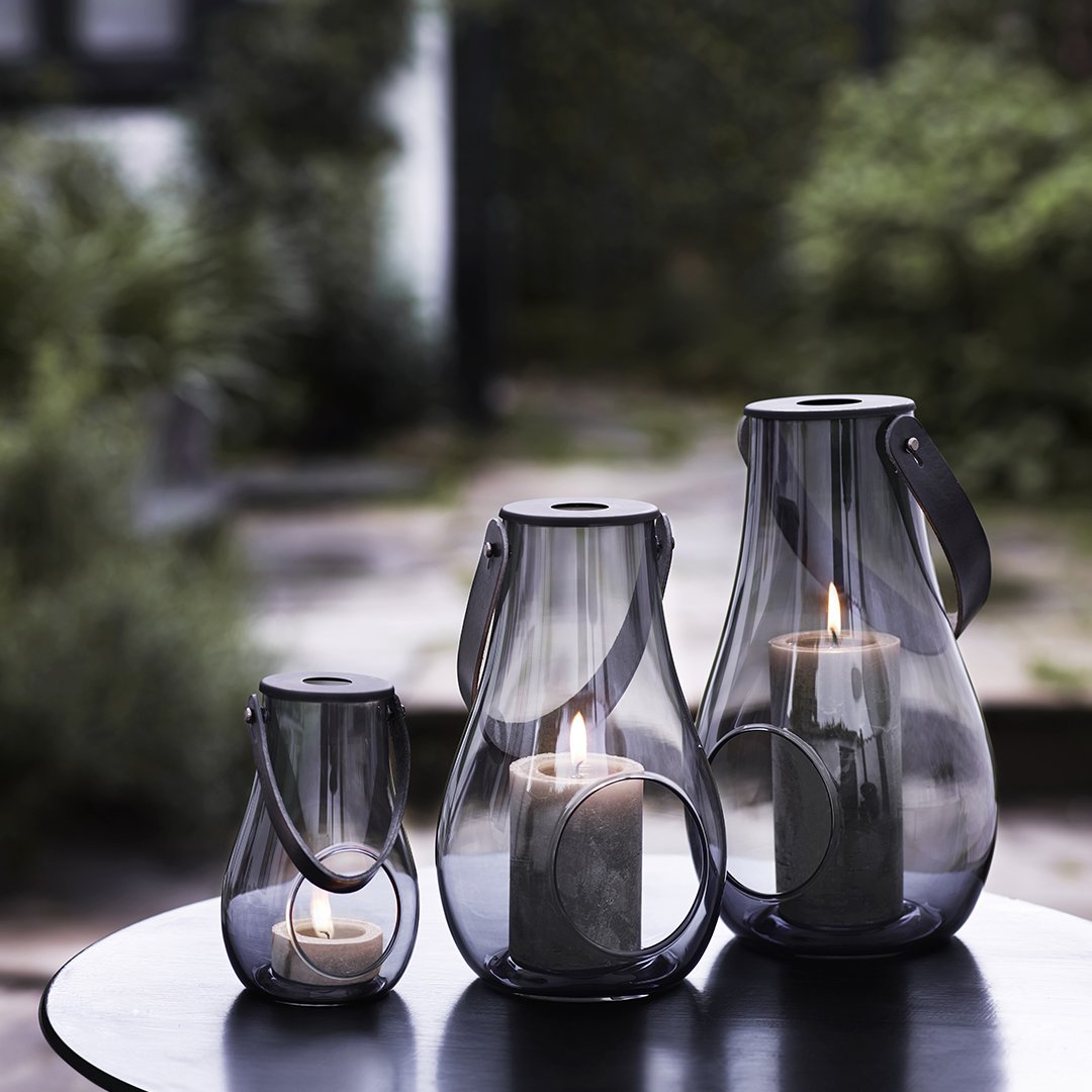 Set of three elegant, translucent glass lanterns in smoky gray, featuring minimalist design and soft candlelight glow.