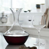 Clear glass decanter with a dark red base, paired with a transparent wine glass, accentuating elegant simplicity.