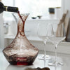 Artisan red glass wine decanter with intricate swirls, accompanied by elegant clear crystal wine glasses.