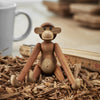 Wooden monkey figurine with natural brown hues and smooth textures, set on wood shavings. Perfect for rustic decor.