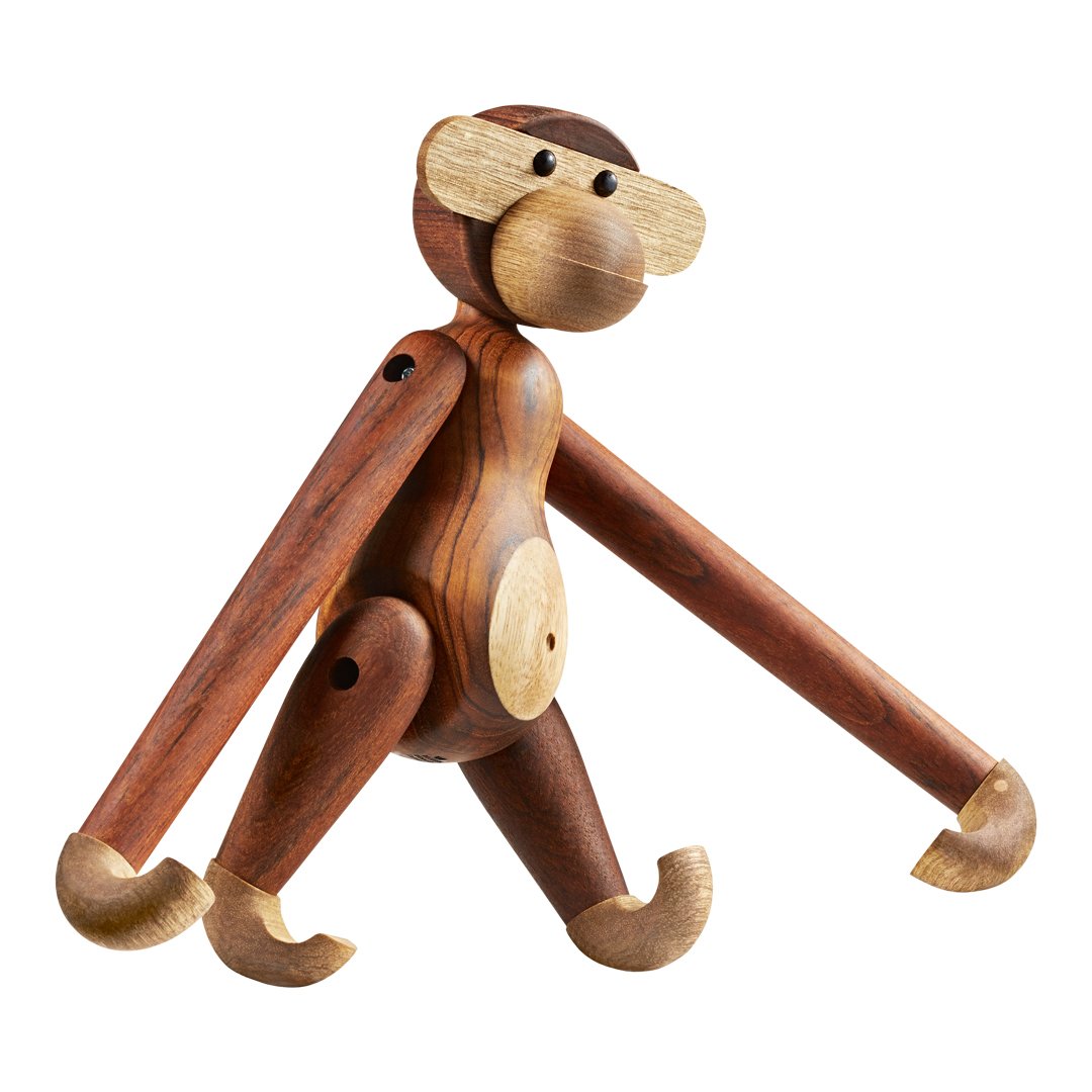 Wooden monkey figurine in rich brown tones with lighter accents and smooth, rounded patterns. Playful design and posture.