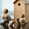Wooden bird figurines in natural tones with contrast, featuring smooth shapes and a charming textured wooden birdhouse.