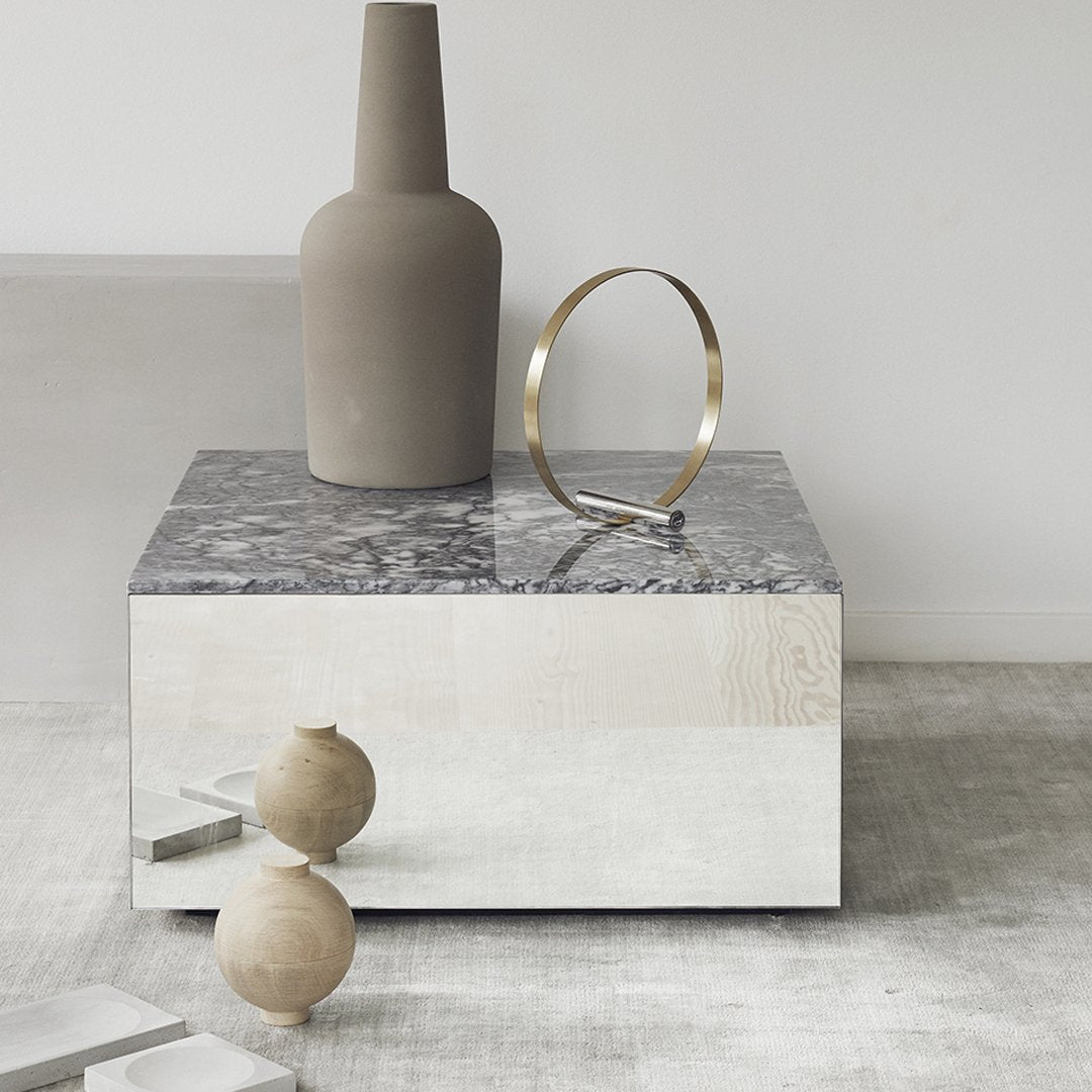 Modern coffee table with a glossy mirrored finish and grey marble top, complemented by neutral decorative accents.