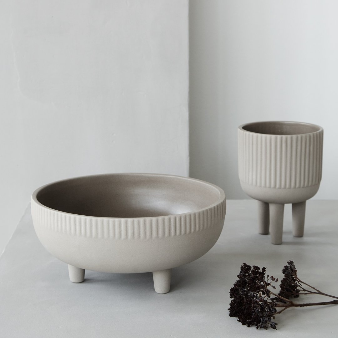 Gray ceramic bowls with ribbed patterns, featuring a matte finish and rounded shapes, styled elegantly in a minimalist setting.