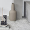 Gray ceramic vase with a modern, minimalist design on a textured light gray surface, complemented by black accents.