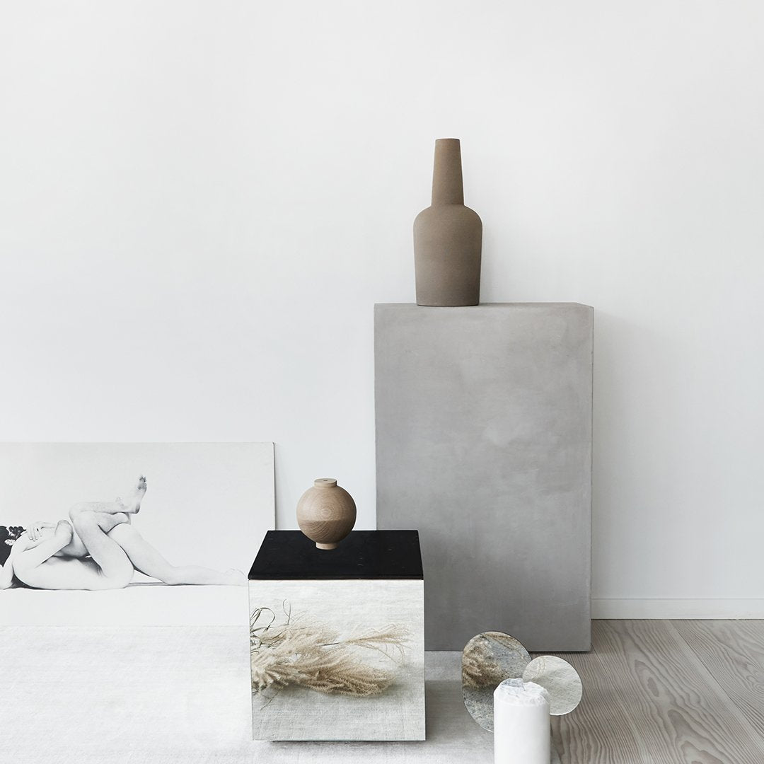 Sleek neutral tones with beige, gray, and black patterns; modern vases and decor on minimalist surfaces.