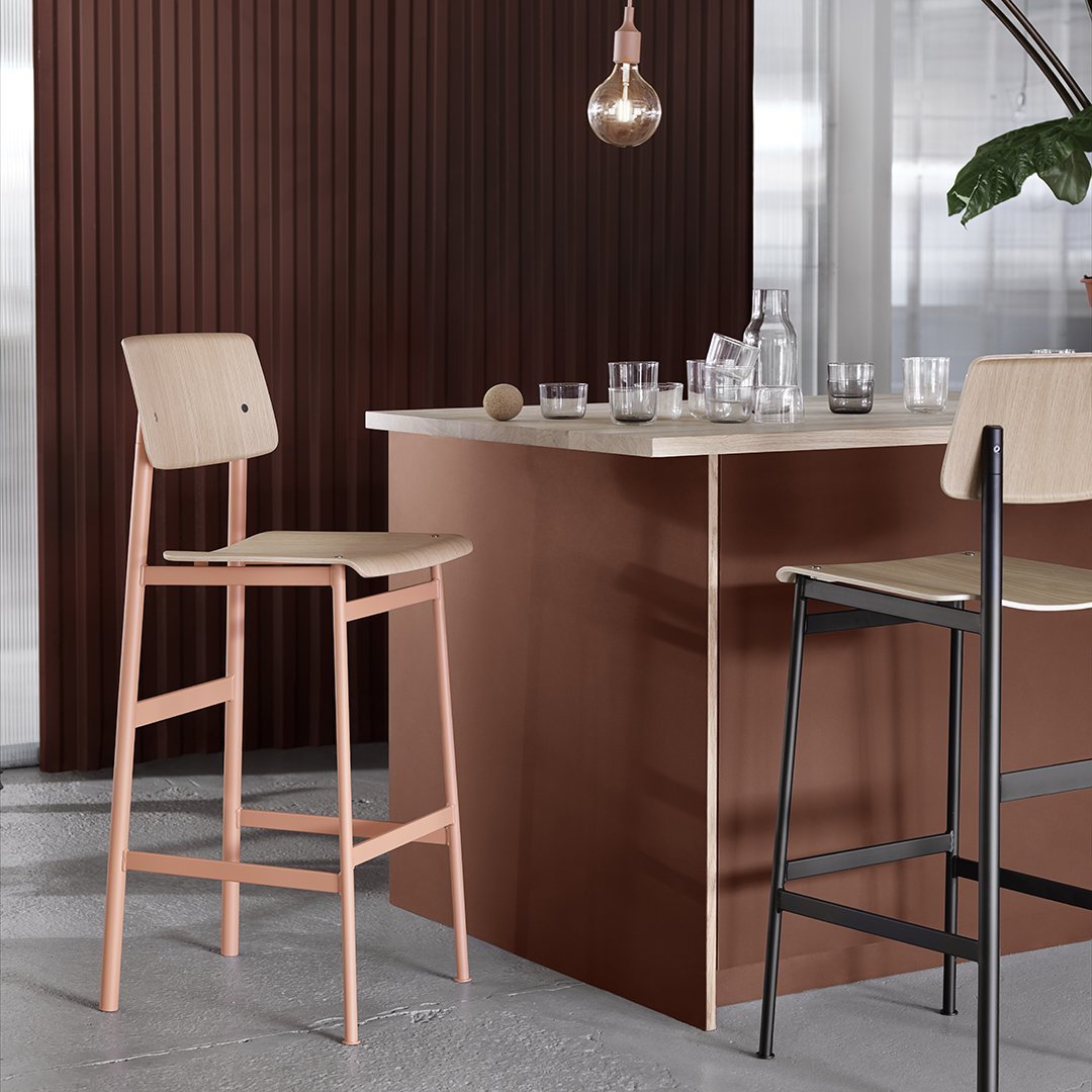 "Modern bar stools in soft pink and natural wood against a rich brown backdrop, featuring sleek lines and minimalist design."