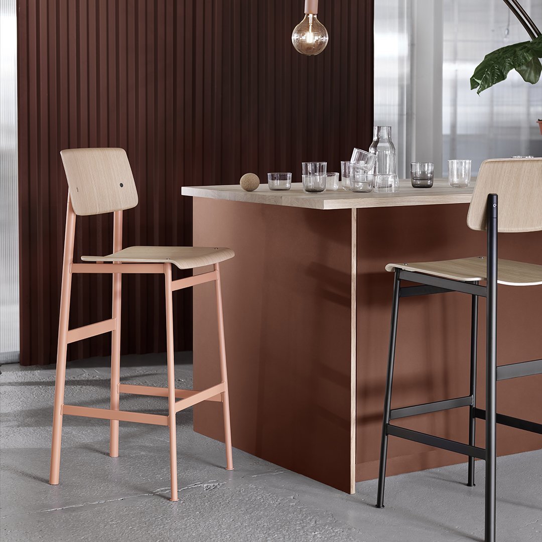 Modern bar stools in soft beige with a sleek, pink frame and a contrasting black frame against a rich brown backdrop.