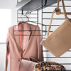 Blush pink suit jacket, beige handbag, and leopard print bag displayed on a sleek black hanger against a modern backdrop.