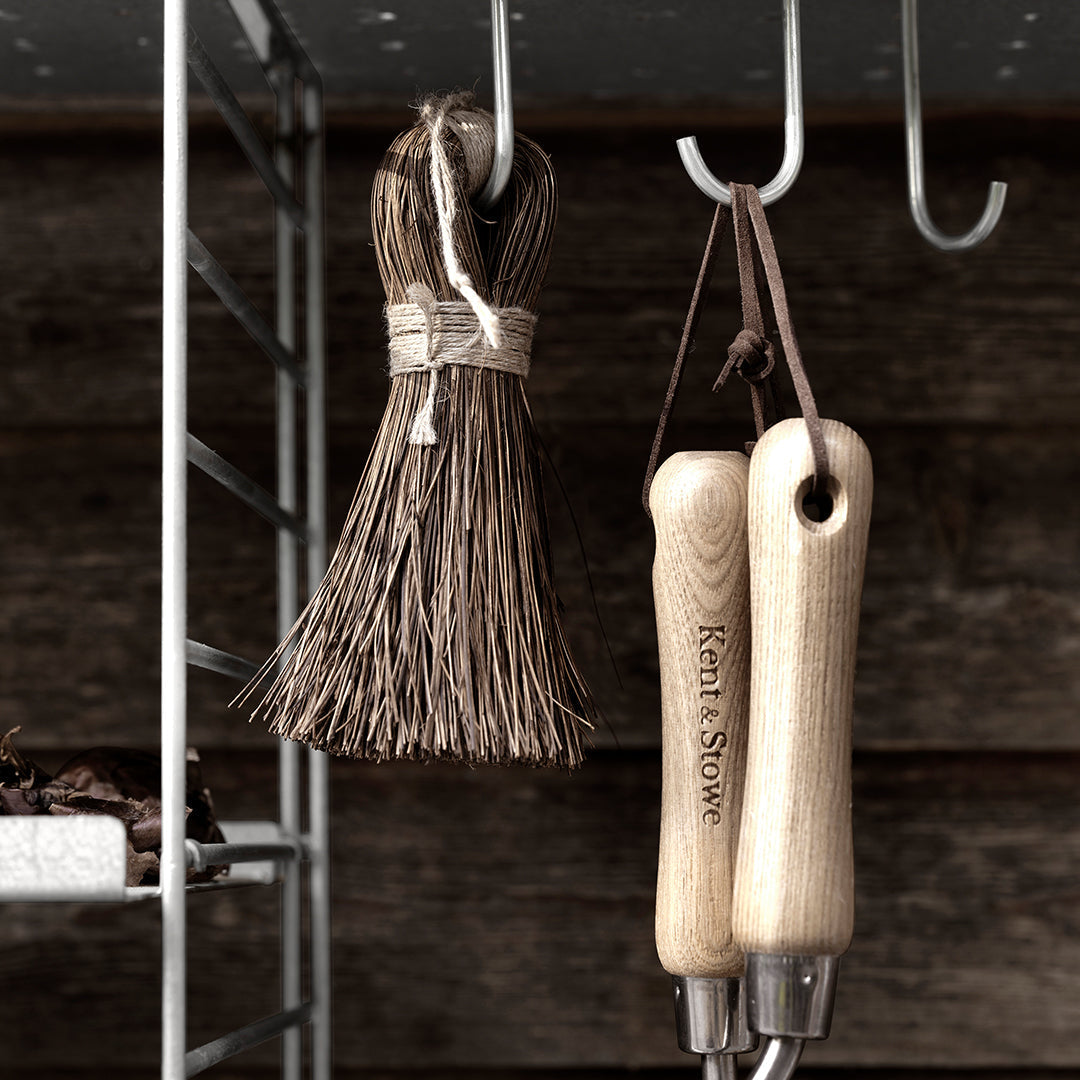 Natural brown broom with wooden handles, displayed against a rustic wooden backdrop. Subtle textures and earthy tones.
