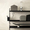 "Minimalist black shelving with gray storage boxes and a sleek design against a light wood backdrop."