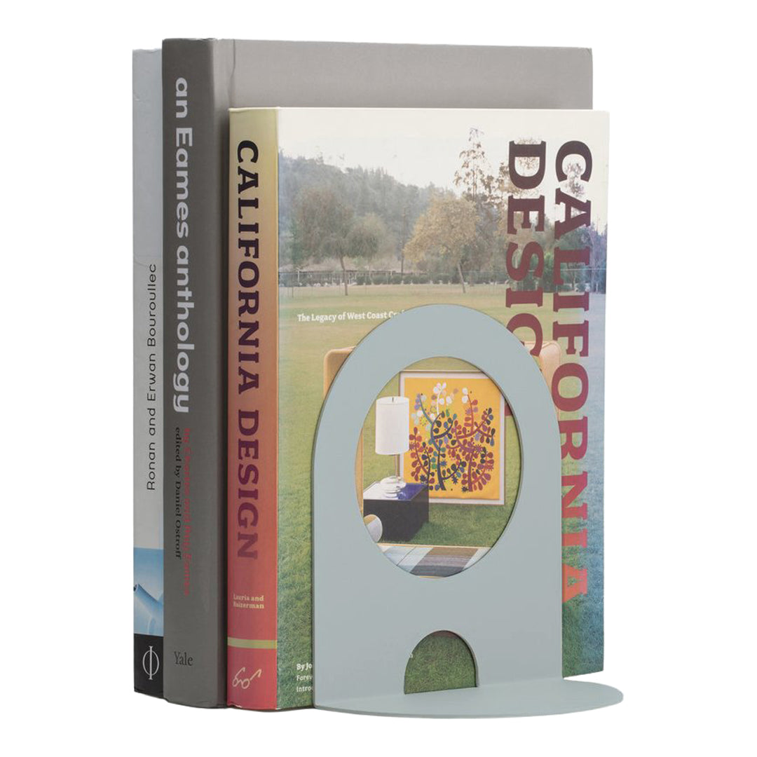 Modern pastel blue bookend with a cut-out design, complementing colorful book spines and neutral background colors.