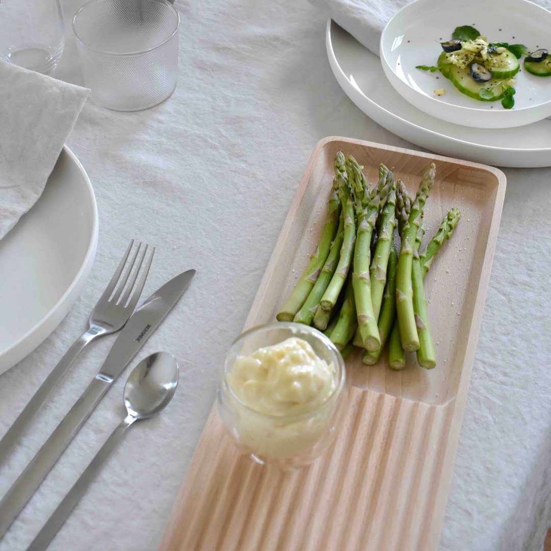 Elegant beige serving tray with ridged texture, showcasing vibrant green asparagus and creamy dip. Soft linen backdrop.