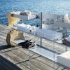 Stylish silver metal shelving with white towels and natural beige accents, set against a serene blue water background.