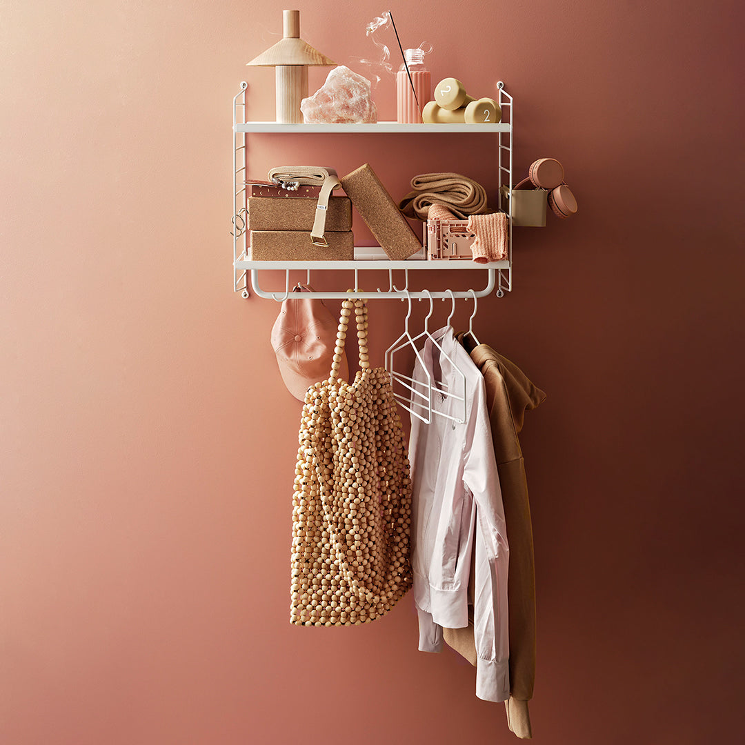 "Chic wall shelf with warm coral tones, golden textures, and soft neutrals showcasing stylish accessories and clothing."