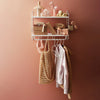 "Chic wall shelf with warm coral tones, golden textures, and soft neutrals showcasing stylish accessories and clothing."
