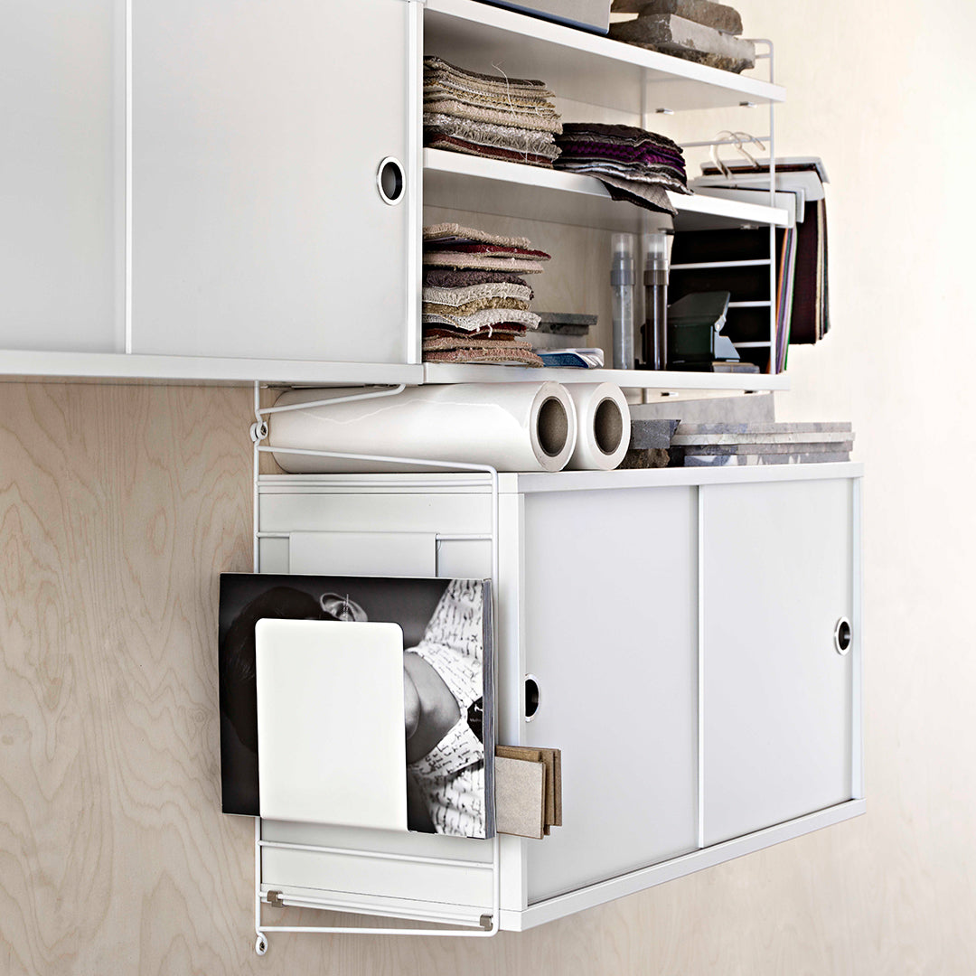 White shelving unit with clean lines, showcasing various fabric swatches and rolls, organized in a minimalist design.