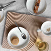 Minimalist wood serving board with concentric circles, accompanied by white dishes and a warm neutral color palette.