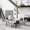 Modern dining room with black and beige chairs, white table, and brown pendant lights against a minimalist backdrop.