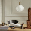 White textured glass pendant lamp with gold accents, illuminating a stylish workspace. Elegant and modern design.