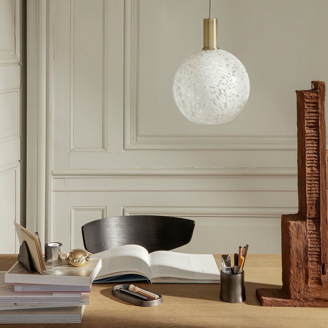 White textured globe pendant light with gold accents, surrounded by a neutral color palette and natural materials.