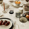 Elegant table setting with earthy tones, textured glassware, and fresh produce in vibrant colors.