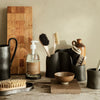 Elegant earthy tones with black ceramic textures and natural wood patterns create a minimalist kitchen aesthetic.