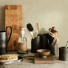 Black ceramic holders, wooden textures, natural tones; minimalist kitchenware with earthy colors and subtle patterns.