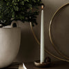 Mint green candle with a sleek design, set against a neutral backdrop, complemented by gold and earthy elements.