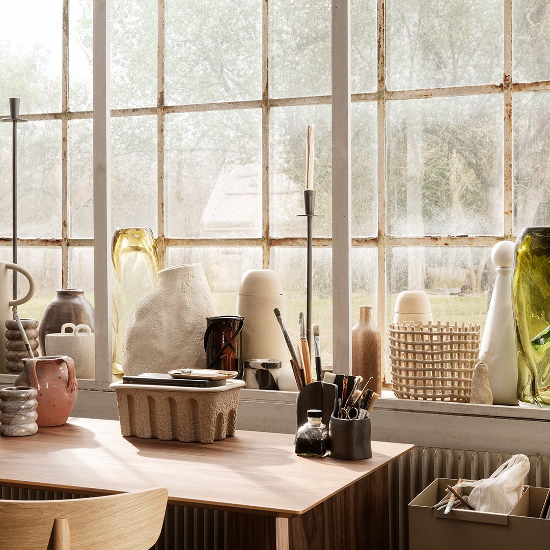 "Collection of textured vases in soft neutrals, greens, and browns, arranged by a sunlit window."
