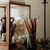 "Colorful tapered candles in a glass jar, showcasing warm tones of brown, cream, and teal against a neutral backdrop."
