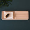 Light wooden rectangular tray with ridges, featuring a white towel and black caviar, set against a dark green surface.