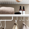 Cozy beige sweater on a white shelf with black and brown spray bottles against a neutral backdrop.
